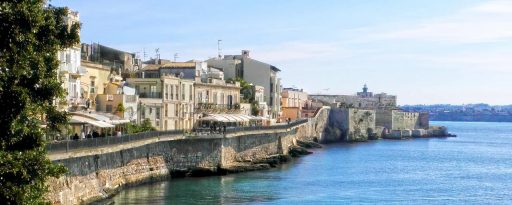 The coastline of Ortygia showing old historic buildings on the left and the Mediterranean sea on the right in Sicily