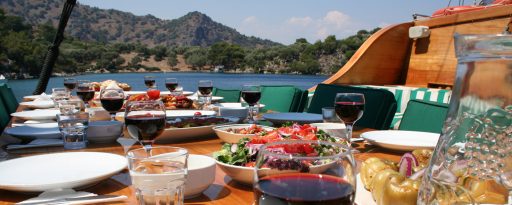 A table set out for a traditional lunch aboard a gulet in Turkey, with the sea and hills in the background