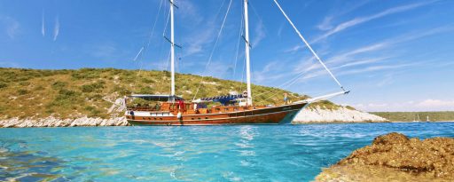 Gulet in a cove with turquoise seas in the foreground on the coast of Croatia