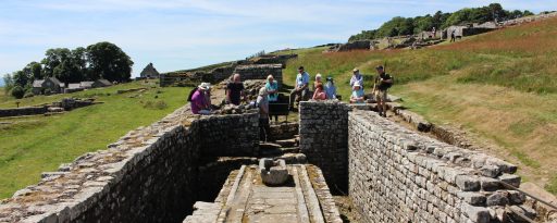 Small group looking into the Roman toilets at the archaeological site of Housesteads on Hadrian's Wall in England