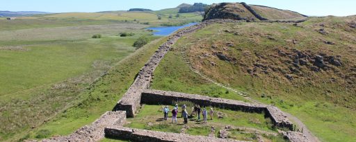 View of a small group standing inside Roman Milecastle 39 during an archaeological tour of Hadrian's Wall in England
