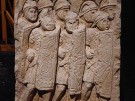 A buff coloured stone relief depiction of Roman legionaries in formation