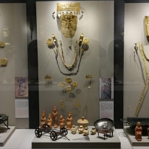 The displays of female graves 262, 458 and 688. You can spot gold diadems, masks, necklaces, pins and ornaments sewn to clothing. Further, you may spot bronze vessels and tools, as well as clay figurines in human and animal shape and bronze miniature models.