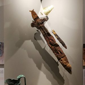 The full display of (male) Grave 774, with helmet, gold eye and mouth covers, gold wrist-cover, iron sword and knife, bronze oinochoe (wine jug), alabastra (perfume jars), terracotta figurines in the shape of a woman and of animals. Ca 540-520 BC.