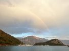 Wide shot showing gulets and sailboats anchored near Gemiler island with BabadaÄź (Father mountain) in the distance and a rainbow above