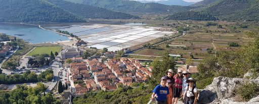 A small group walking on the medieval fortifications at Ston with the old town and salt flats in the background in Croatia