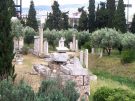 Classical graves lining the streets just outside ancient Athens, with a backdrop of the modern city.