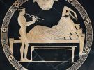 A banqueting scene from an Athenian red-figure cup, showing a reclining reveller and flute-playing boy. Ca. 550 BC, on display in the Louvre at Paris.