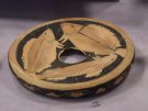 An ancient South Italian Greek fish-plate decorated with three detailed red-figure fish swimming around a central depression hole.