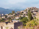 View of the abandoned stone houses of Kayaköy ghost town in Turkey, cascading down a hillside under a hazy sky.