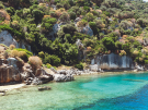 Submerged stone foundations of the ancient Lycian city of Dolichiste visible through the clear turquoise water along the rocky coastline of Kekova Island, Turkey.