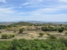 Panoramic view overlooking the ancient ruins of Morgantina in Sicily, with the excavated agora and residential zones set against a distant view of Mount Etna under a blue sky.