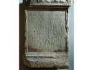 An ancient Roman stone memorial plate featuring a carved Latin inscription dedicated to the god Neptune. The rectangular limestone slab is displayed in the Euphrasian Basilica complex in Poreč, showing weathered textures and a decorative molded border.