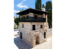 A two-story 13th-century stone Romanesque House in Poreč, Croatia, featuring a prominent dark wooden balcony, a red-tiled roof, and an external stone staircase leading to the first floor.