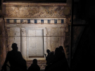 A tour group with guide in silhouette infront to the illuminted façade of Philip's tomb at Vergina, with an extraordinary painted scene above the door.