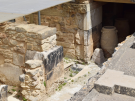 The excavation of the West Magazines storage rooms at the Palace of Knossos in Crete, displaying large ancient ceramic pithoi jars inside a stone cellar.